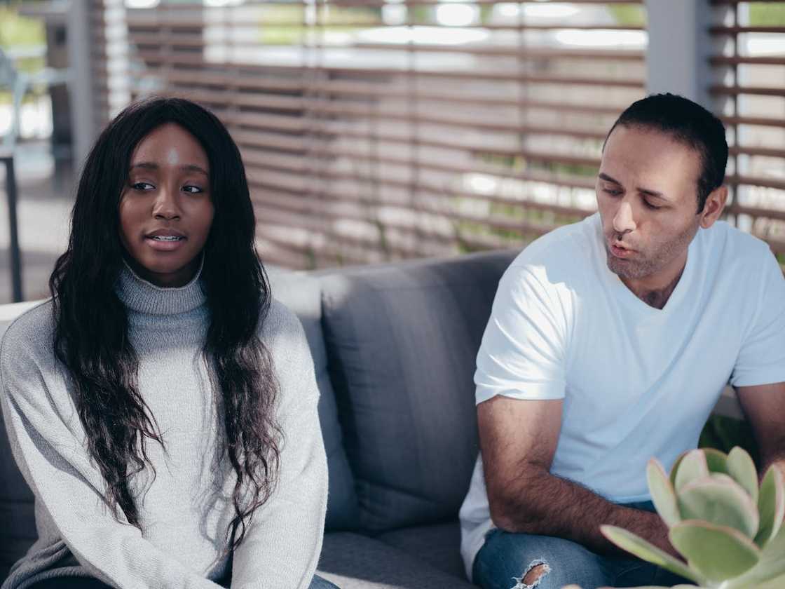 An interracial couple have a conversation while seated outdoors.