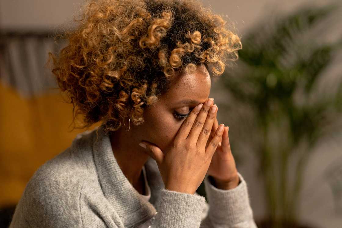 A woman covering her face with her hands, appearing overwhelmed or distressed indoors. A woman covering her face with her hands, appearing overwhelmed or distressed indoors.