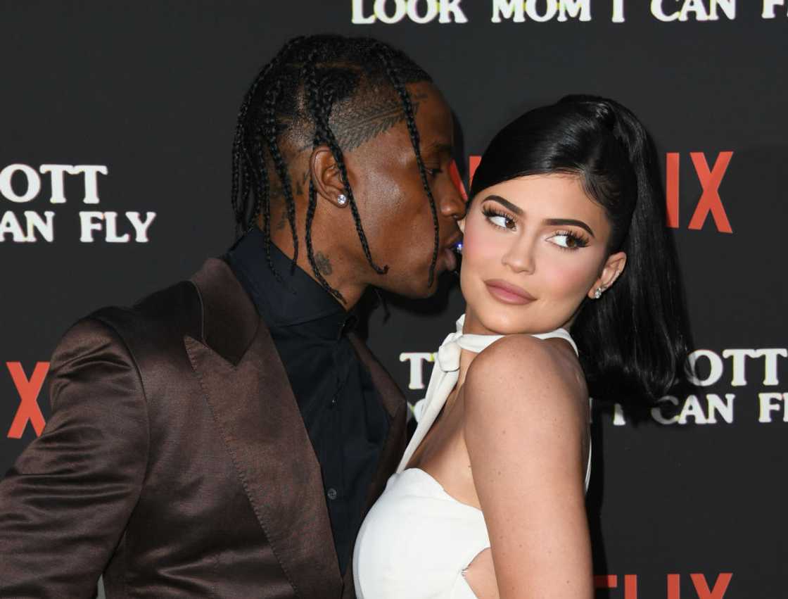 Travis Scott (L) leans to kiss Kylie Jenner (R) at at Barker Hangar Travis Scott (L) leans to kiss Kylie Jenner (R) at at Barker Hangar