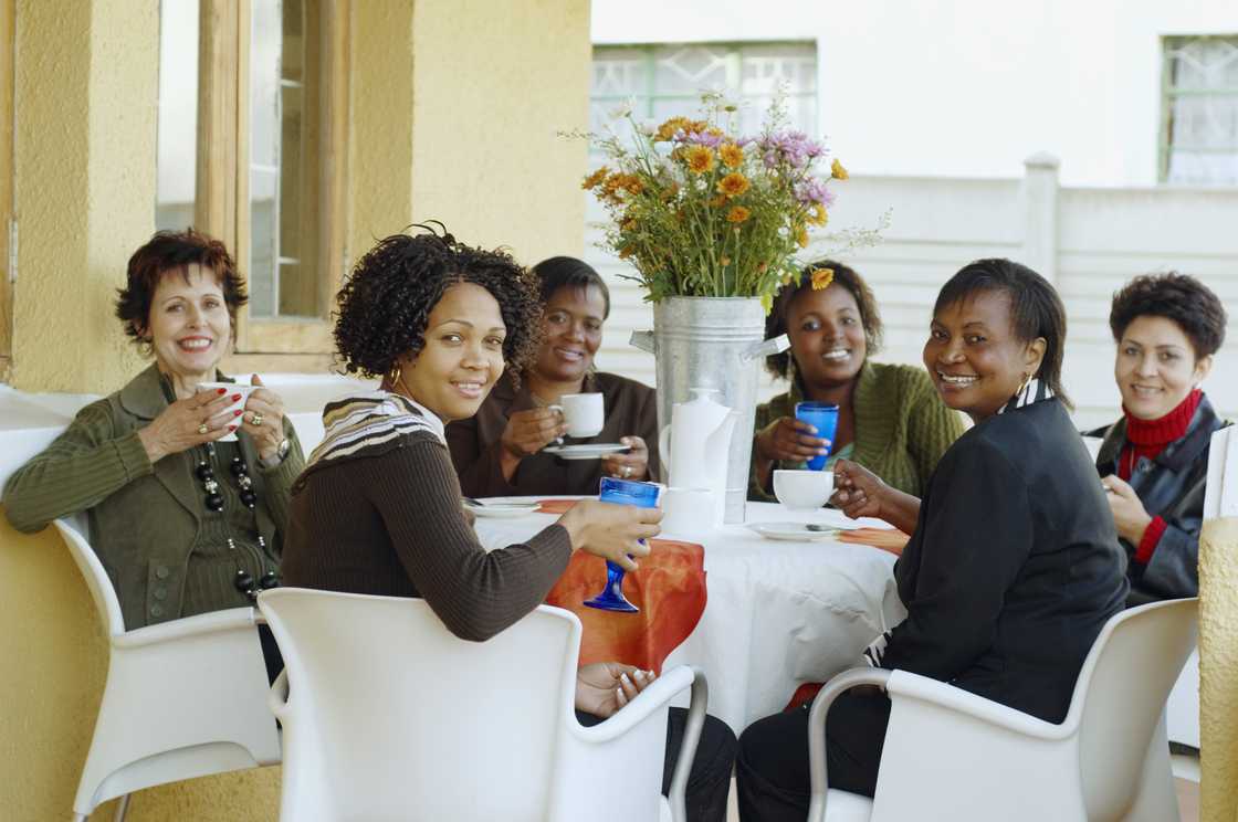 Women gathered in a community hall for a stokvel meeting. Women gathered in a community hall for a stokvel meeting.