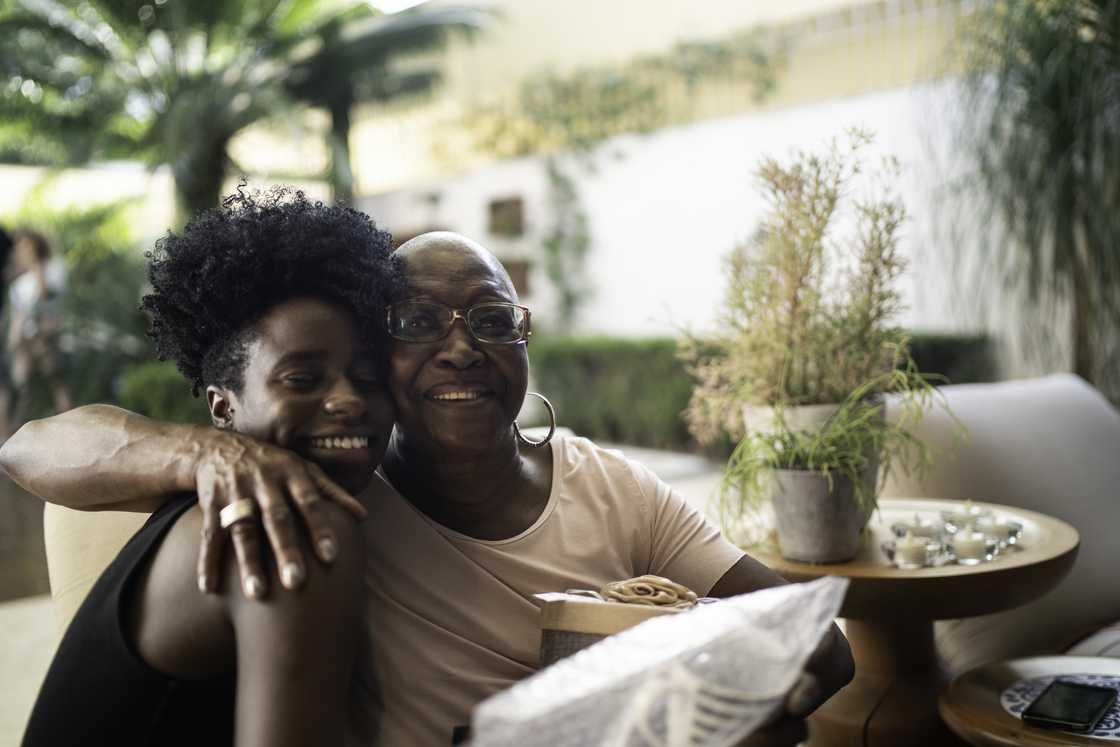 An elderly person and younger person embracing indoors. An elderly person and younger person embracing indoors.