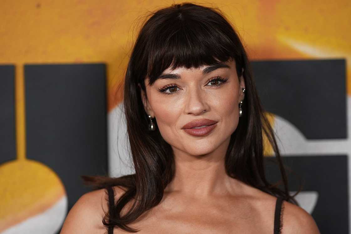 Close-up of a dark-haired woman with blunt bangs wearing small drop earrings. Close-up of a dark-haired woman with blunt bangs wearing small drop earrings.