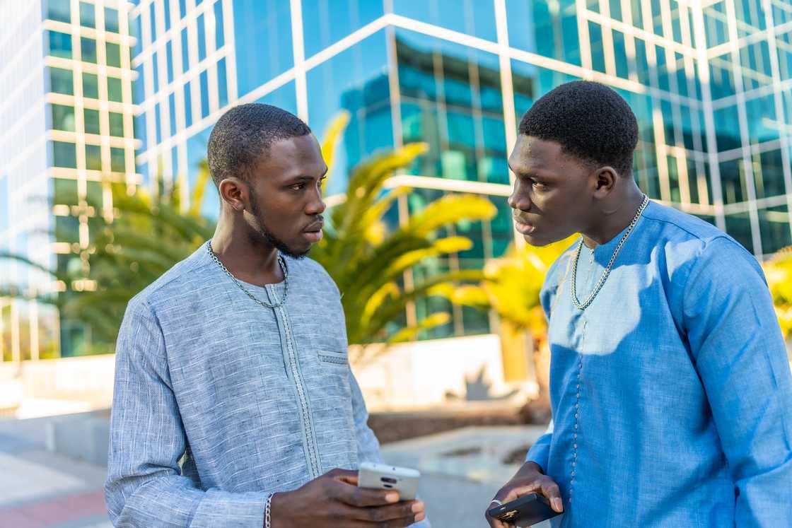 A man talking to his friends as he shows him his phone