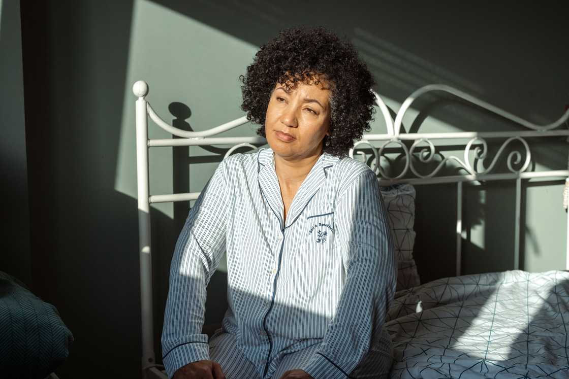A thoughtfull woman sitting on a bed A thoughtfull woman sitting on a bed