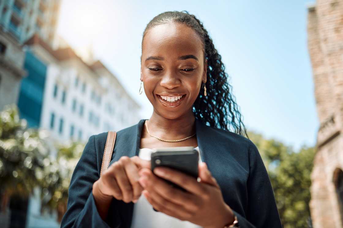 A woman walking in the street while using her phone.