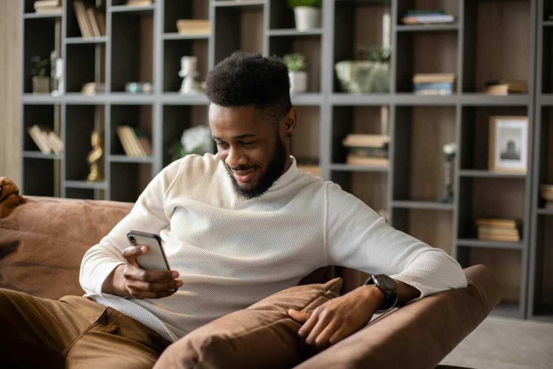 A young man using his phone while sitting on a couch