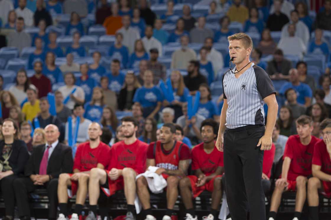 A basketball referee blows a whistle