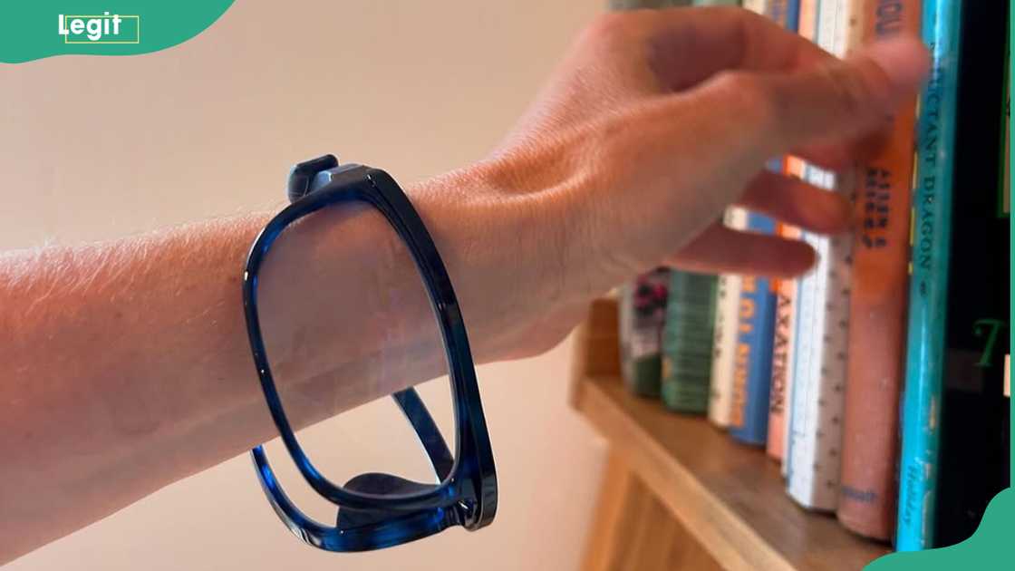 A person’s arm wearing a blue wrist strap that securely holds a pair of eyeglasses