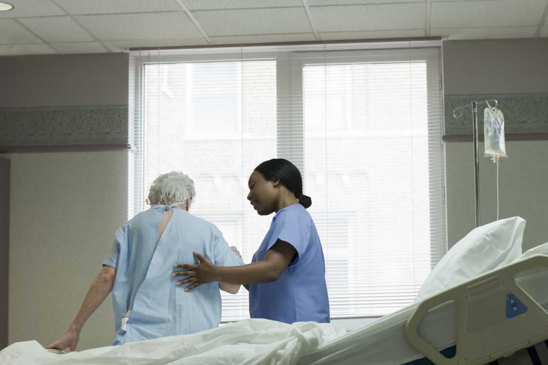 A nurse helping a patient stand up