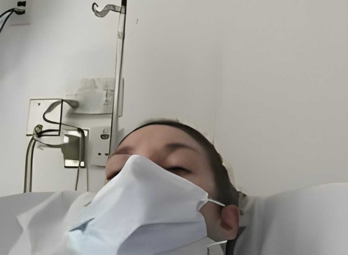 Lindsay Clancy wearing a mask laying on a hospital bed Lindsay Clancy wearing a mask laying on a hospital bed