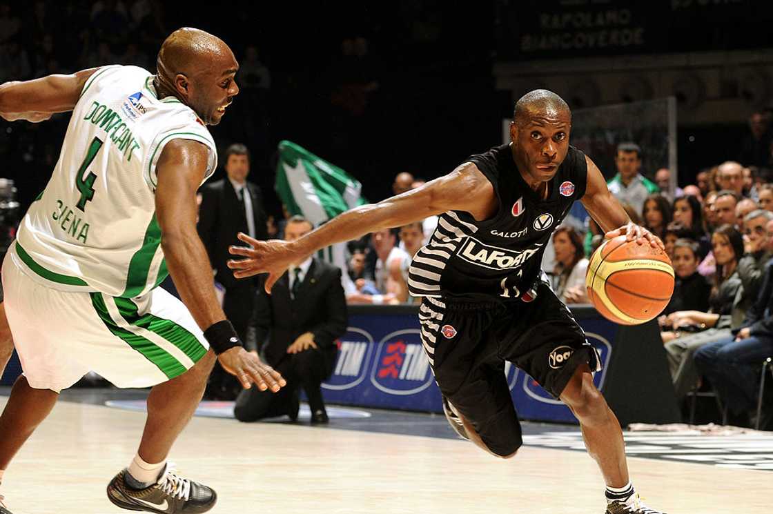 Earl Boykins (R) dribbles past an opponent player