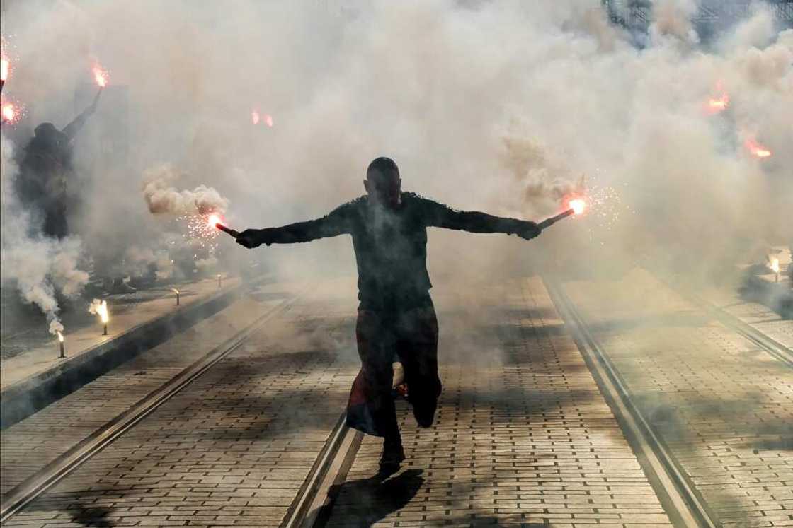 A protester holds burning flares during a demonstration in Nice A protester holds burning flares during a demonstration in Nice