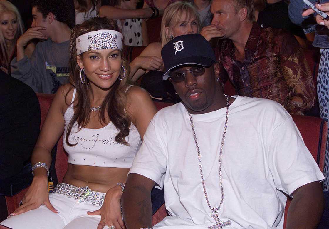Jennifer Lopez in a white bandana and crop top beside Sean Combs in a baseball cap and white tee. Jennifer Lopez in a white bandana and crop top beside Sean Combs in a baseball cap and white tee.