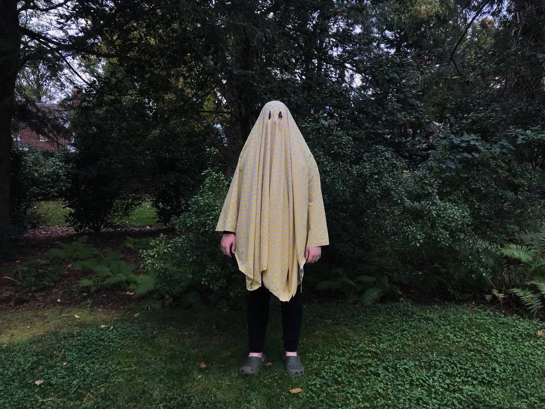 A teenage boy dressed up in a ghost costume. A teenage boy dressed up in a ghost costume.