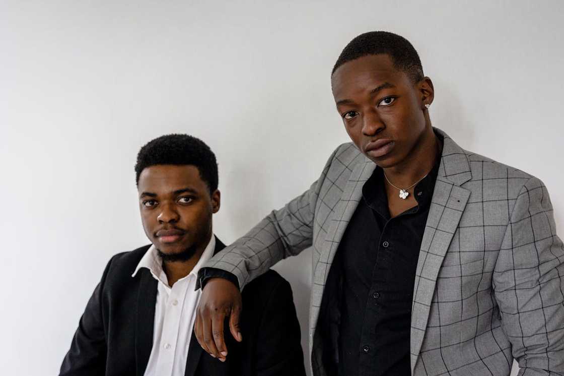 Two men in suits stand side by side, looking at the camera.