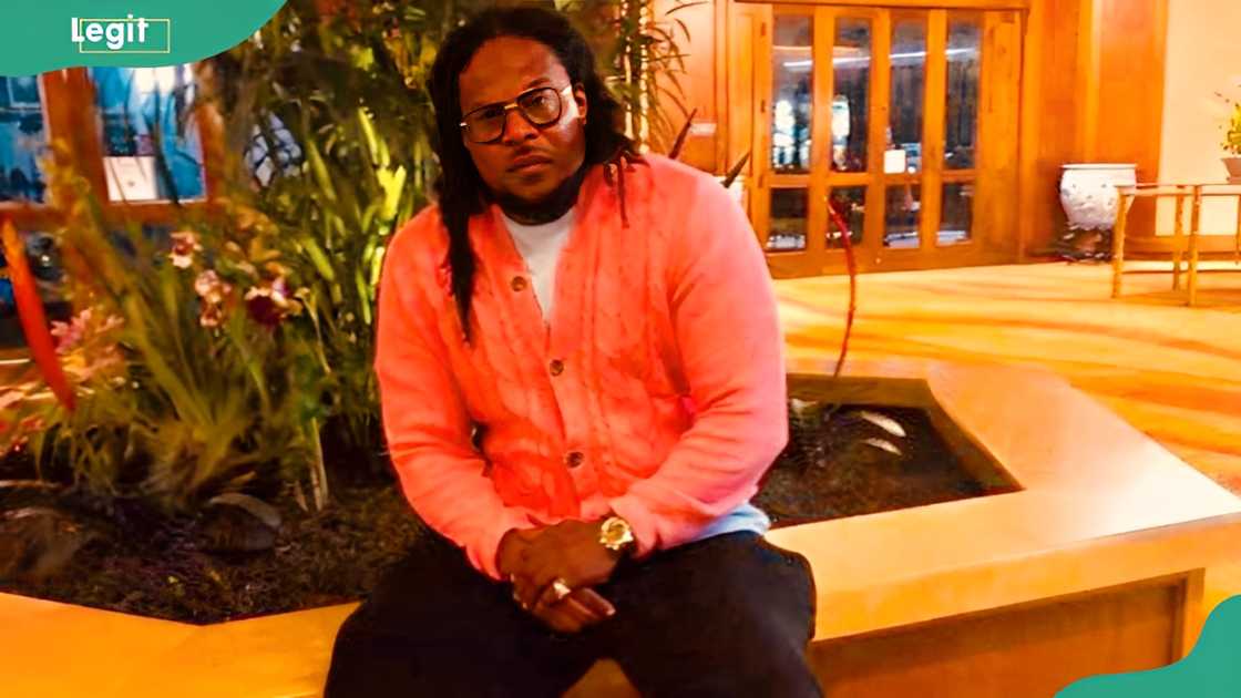 Rapper NOE looks on as he sits on a slab outside a mall Rapper NOE looks on as he sits on a slab outside a mall