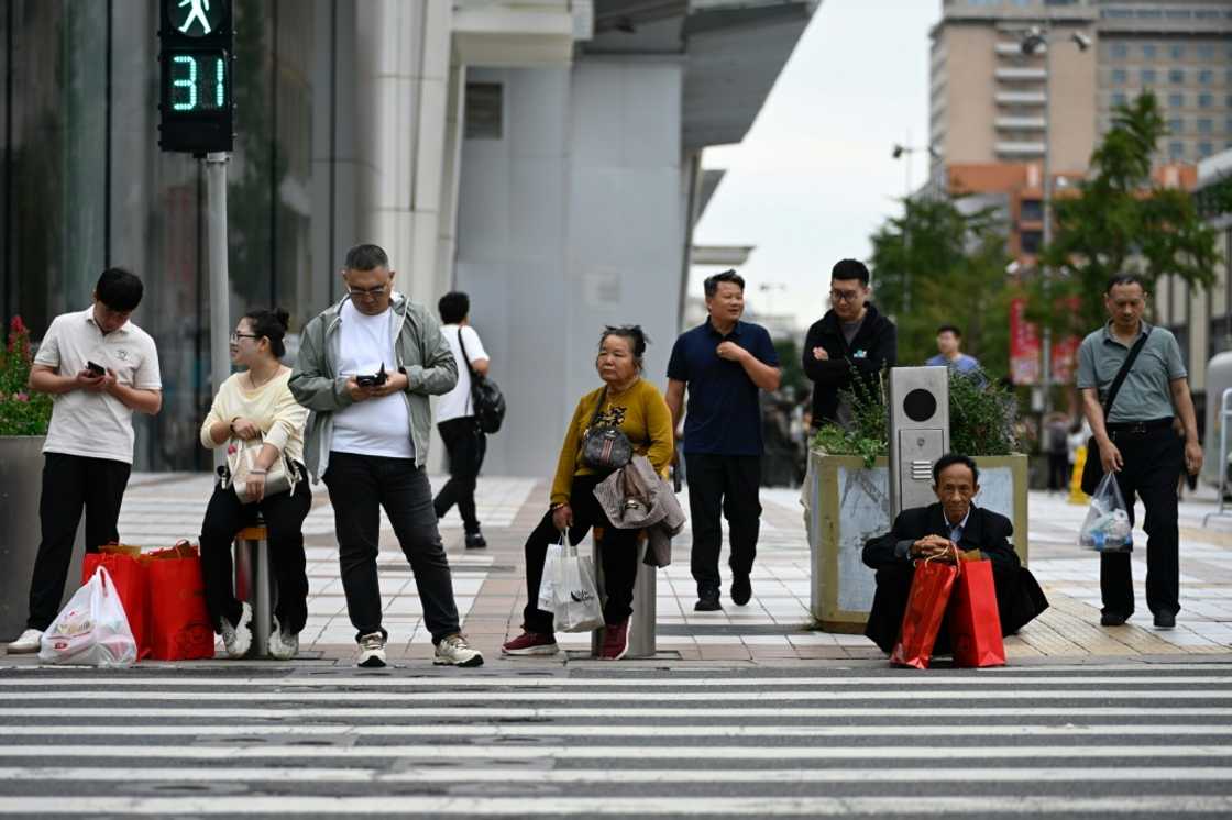 People wait to cross a street in a shopping area in Beijing. China's industrial production and retail sales growth slumped further last month, official data showed on September 15, missing forecasts and highlighting prolonged challenges in the world's second-largest economy People wait to cross a street in a shopping area in Beijing. China's industrial production and retail sales growth slumped further last month, official data showed on September 15, missing forecasts and highlighting prolonged challenges in the world's second-largest economy