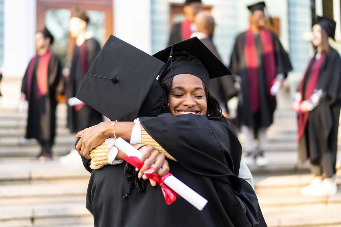 Graduates hugging each other after receiving their diplomas Graduates hugging each other after receiving their diplomas