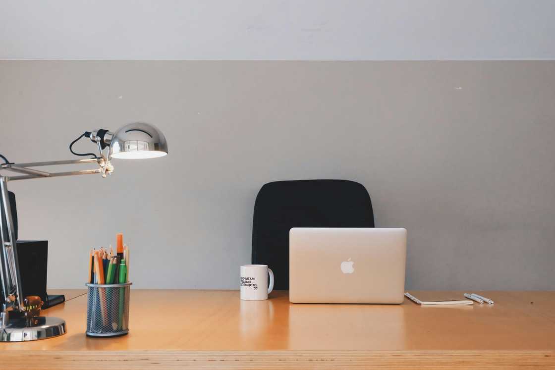 A silver MacBook on a desk with a silver lighting fixture