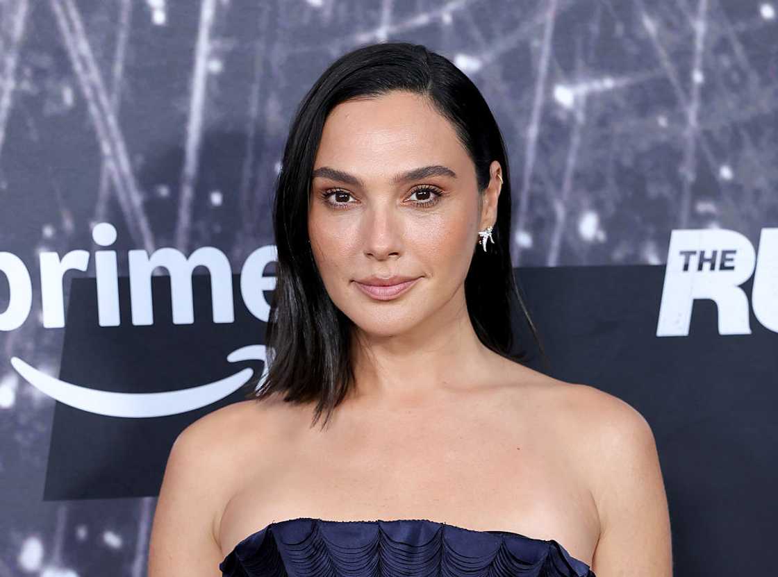 A dark-haired woman poses in a strapless navy dress in front of an Amazon Prime backdrop.