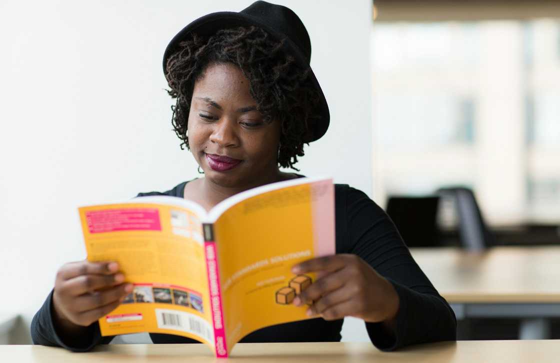 A young lady in a hat reading a book