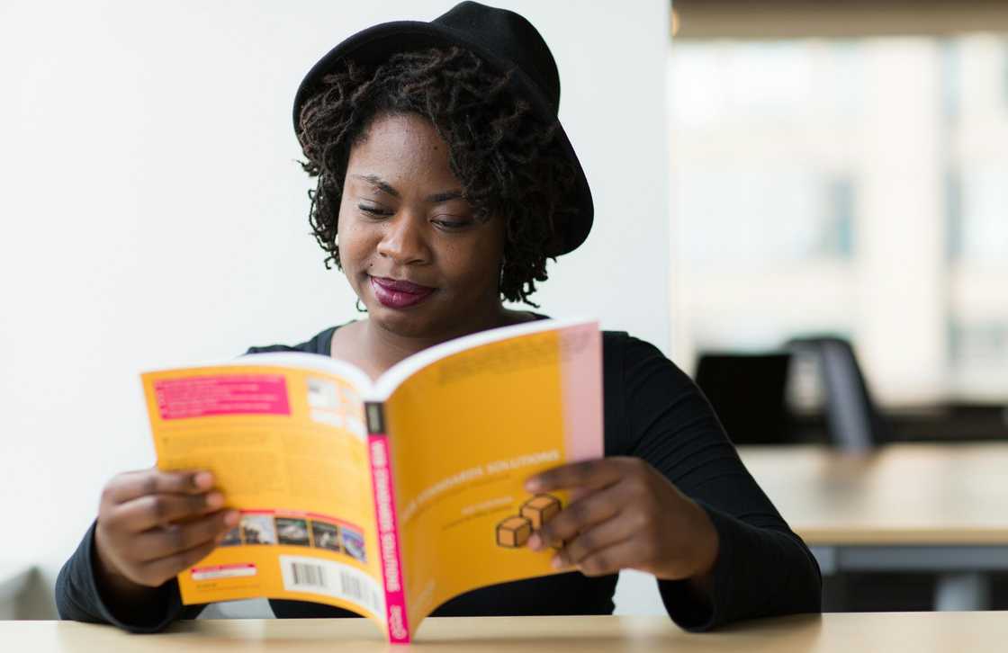 A young lady in a hat reading a book A young lady in a hat reading a book