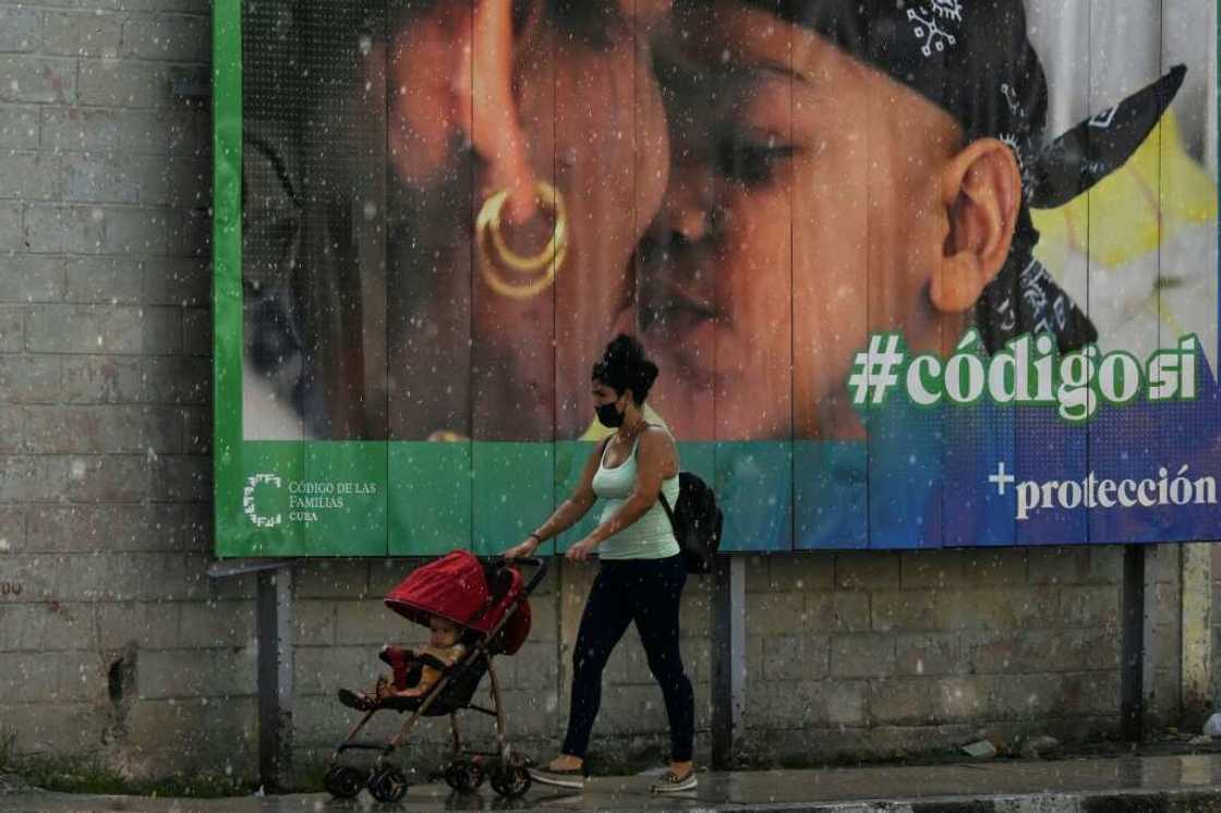 A woman and her baby walk past a banner in Havana promoting a mew family code that legalizes same-sex marriage and other rights A woman and her baby walk past a banner in Havana promoting a mew family code that legalizes same-sex marriage and other rights