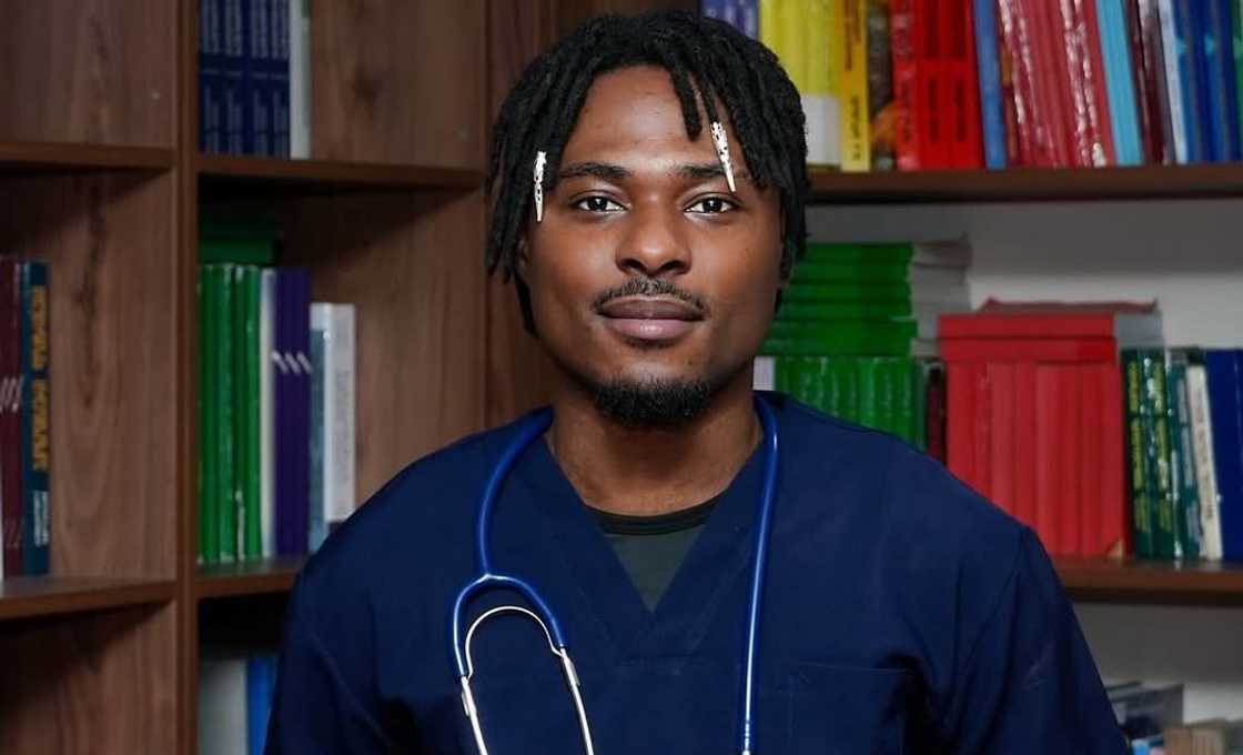 Faith from BBNaija poses in scrubs and a stethoscope in front of a bookshelf. Faith from BBNaija poses in scrubs and a stethoscope in front of a bookshelf.