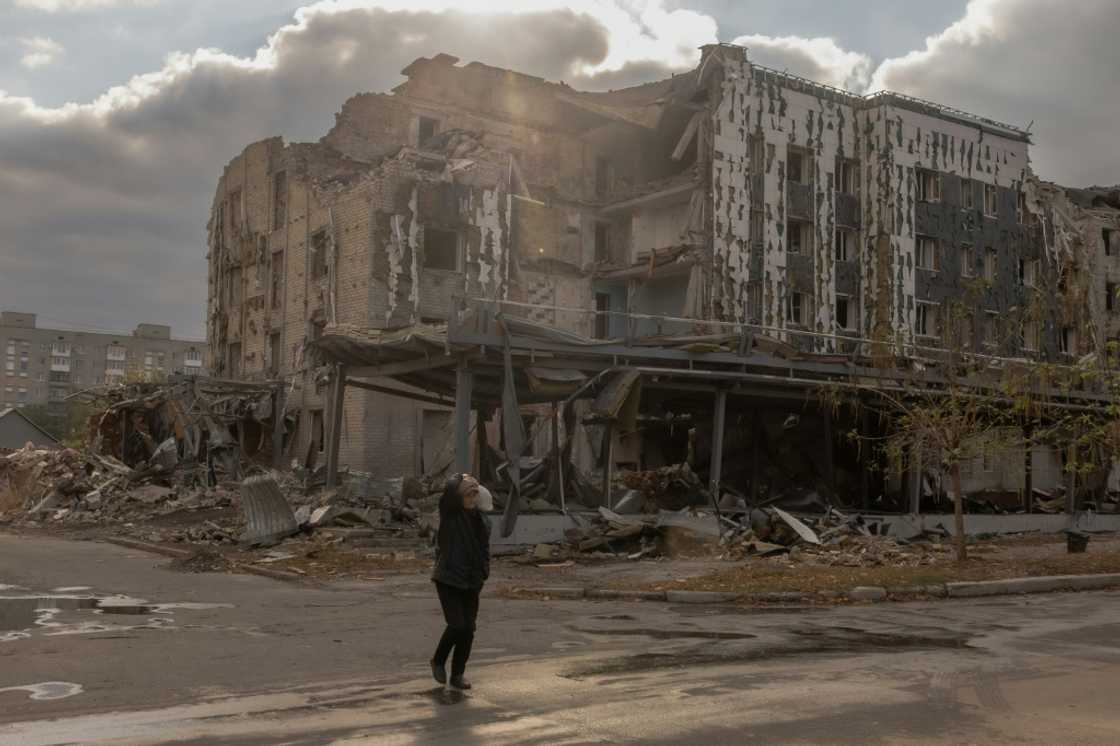 An elderly woman walks past damaged buildings in the town of Pokrovsk in the eastern Donetsk region