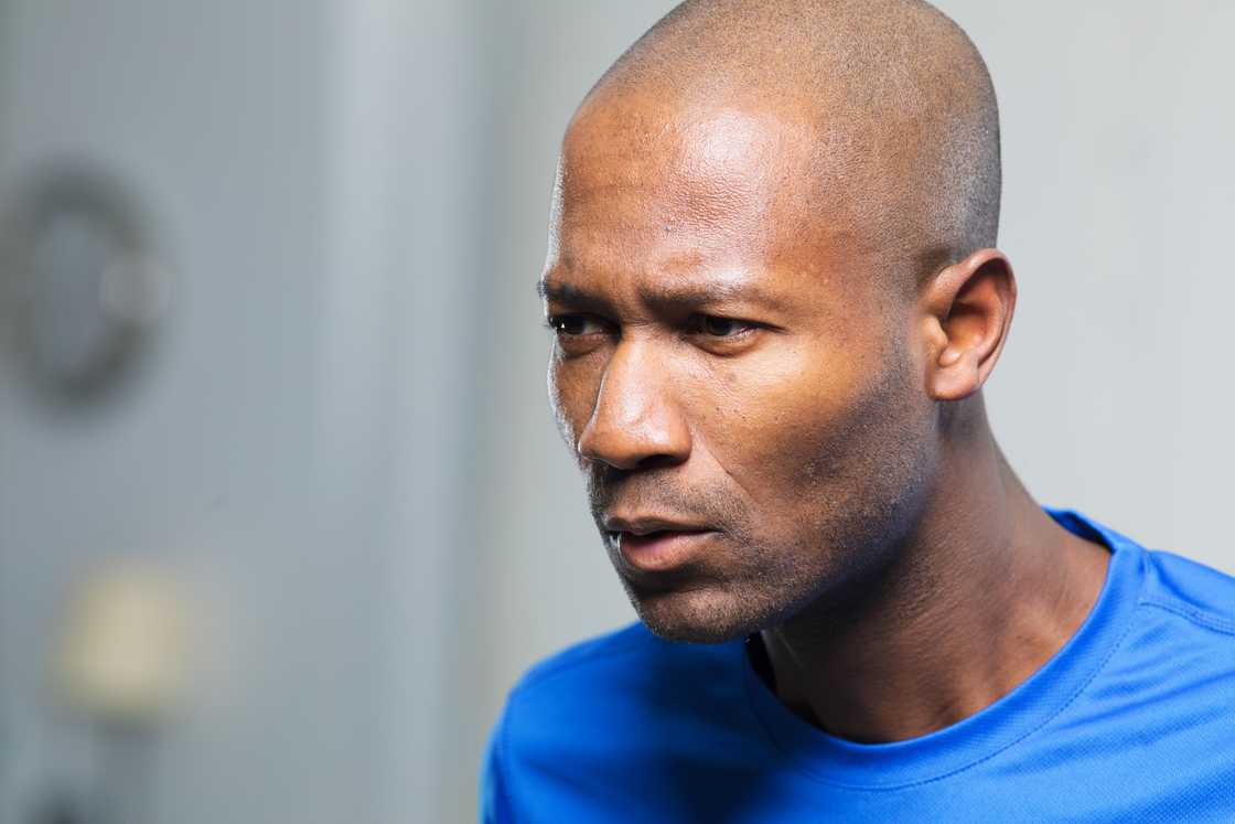 A middle-aged man looking forward with a frown.