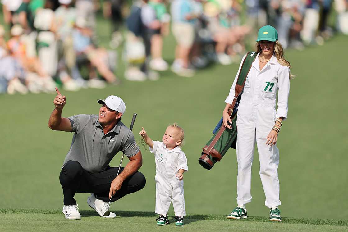 Brooks Koepka gestures alongside his wife, Jena Sims, and their son