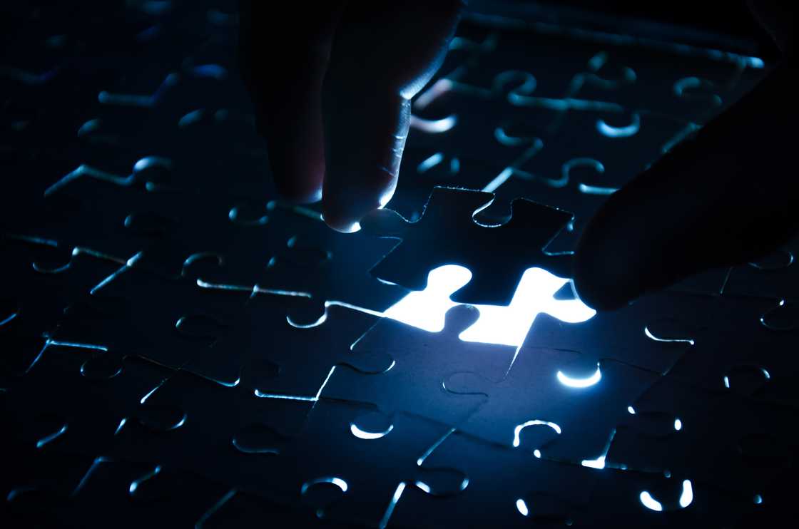 A person finishing a puzzle in the dark. A person finishing a puzzle in the dark.