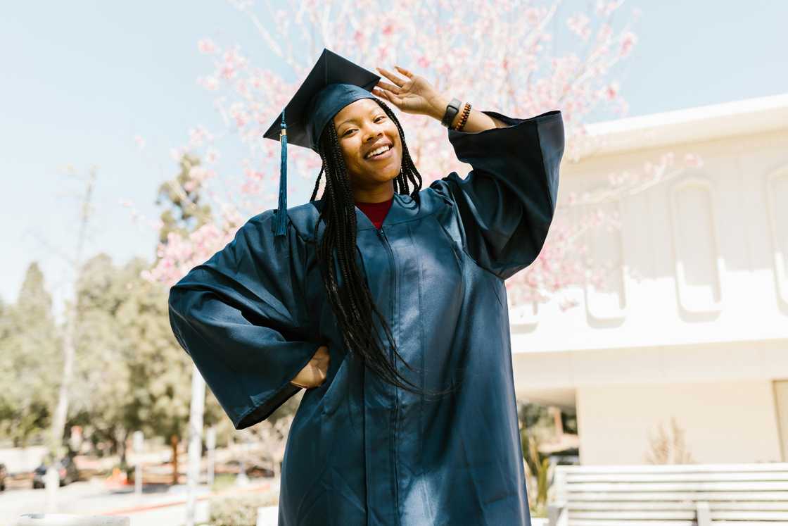 A lady wearing a graduation attire posing for a photo A lady wearing a graduation attire posing for a photo