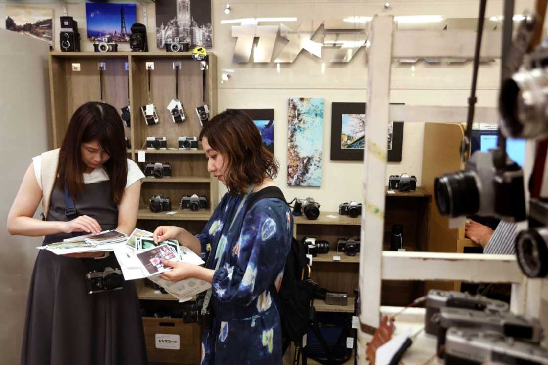 Yuriko Yamada skims  through her prints with her friend at a camera shop in Yokohama, Kanagawa prefecture