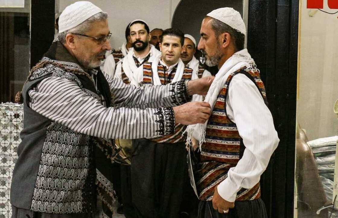 Moutaz Boulad (L), leader of the "Bab al-Hara" traditional Syrian "Arada" dance troupe, assists members as they gear up to perform