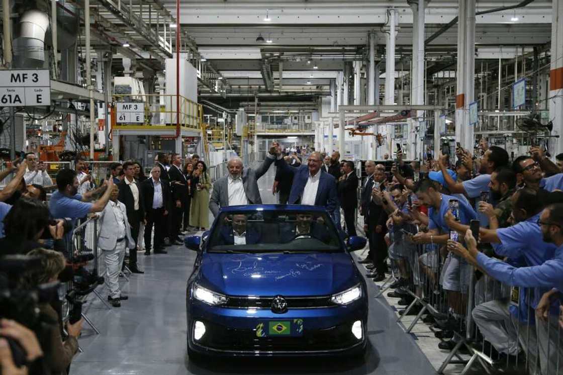 Brazilian President Luiz Inacio Lula da Silva (L) and his vice-president, Geraldo Alckmin, greet workers as they visit the Volkswagen car factory