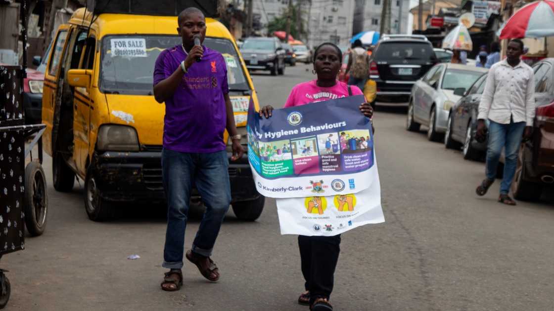 Two social workers walk while educating locals on a door-to-door campaign. Two social workers walk while educating locals on a door-to-door campaign.