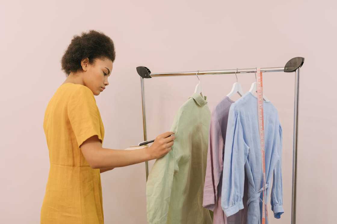 A fashion designer examining garments hanging on a clothing rack.