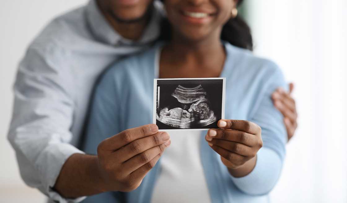 A couple holding an ultrasound photo. A couple holding an ultrasound photo.