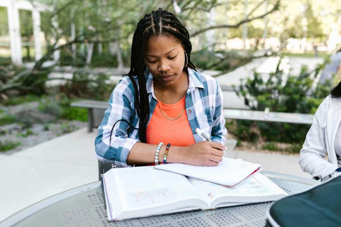 A woman writing on a notebook.