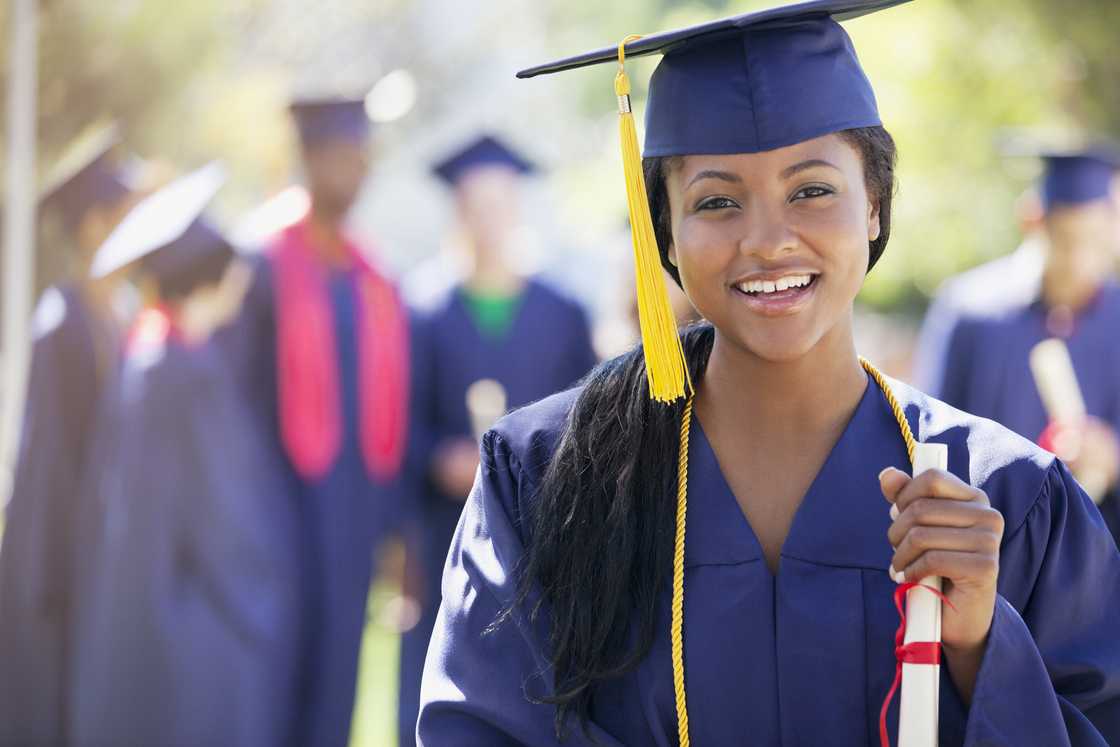A smiling graduate holding a diploma A smiling graduate holding a diploma