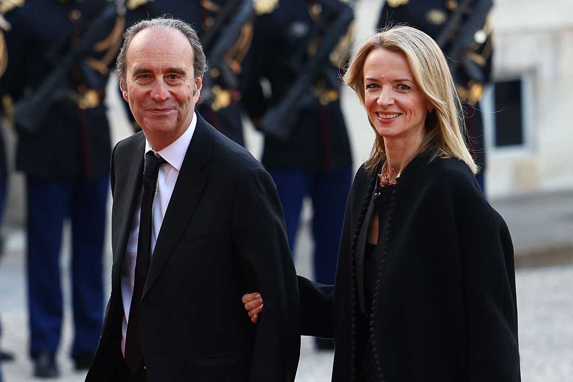 Xavier Niel and Delphine Arnault walking hand in hand at the Elysee Palace