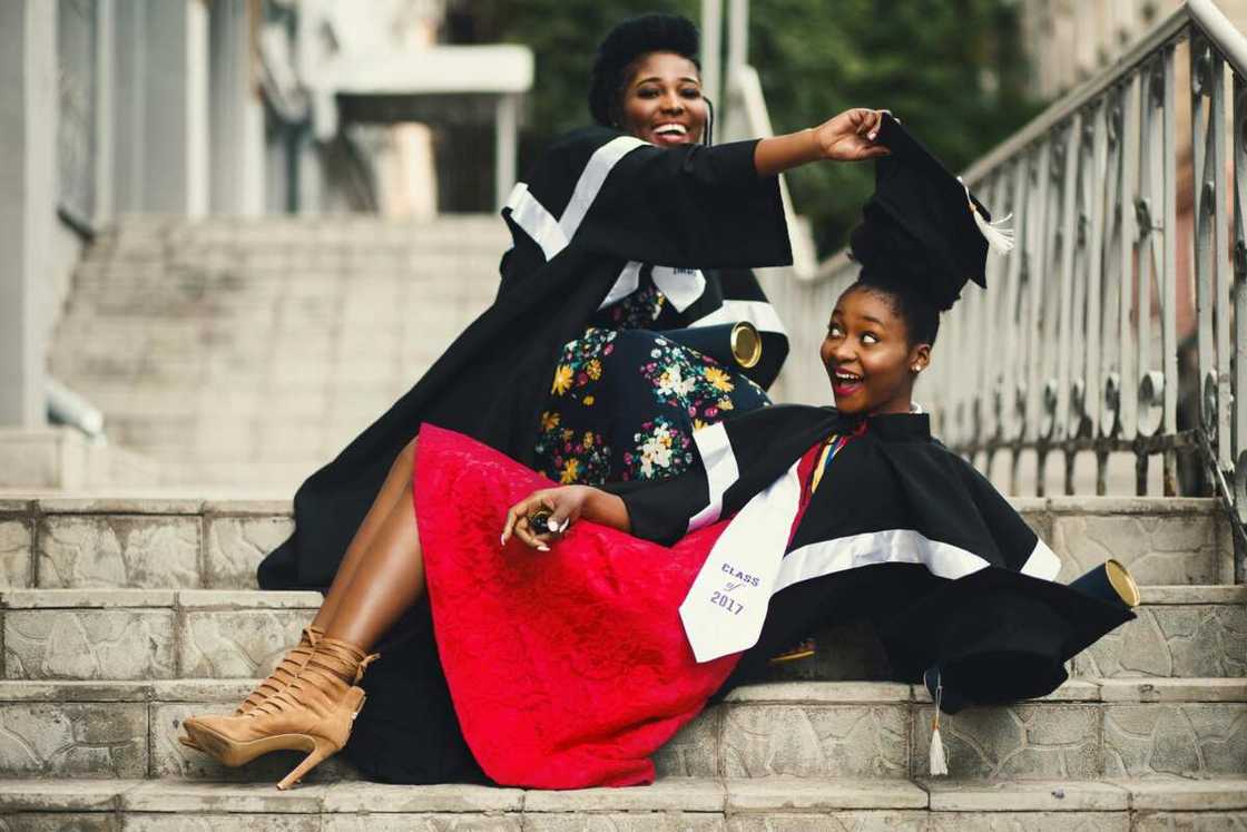 Two ladies wearing graduation gowns on the stairs