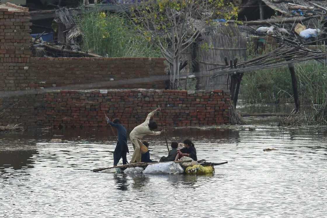 Children use a raft to make their way in a flooded area of Sukkur