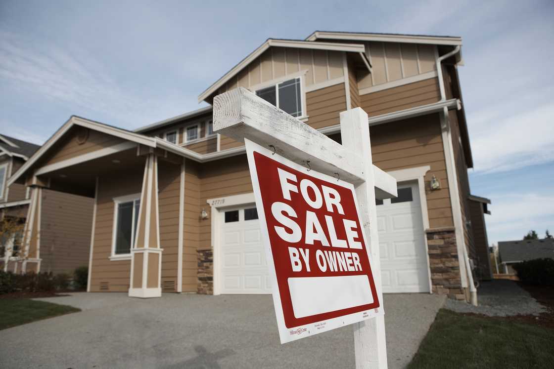 A suburban house with "For Sale By Owner" sign