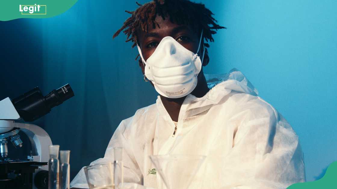 A man in a lab wearing protective gear and mask