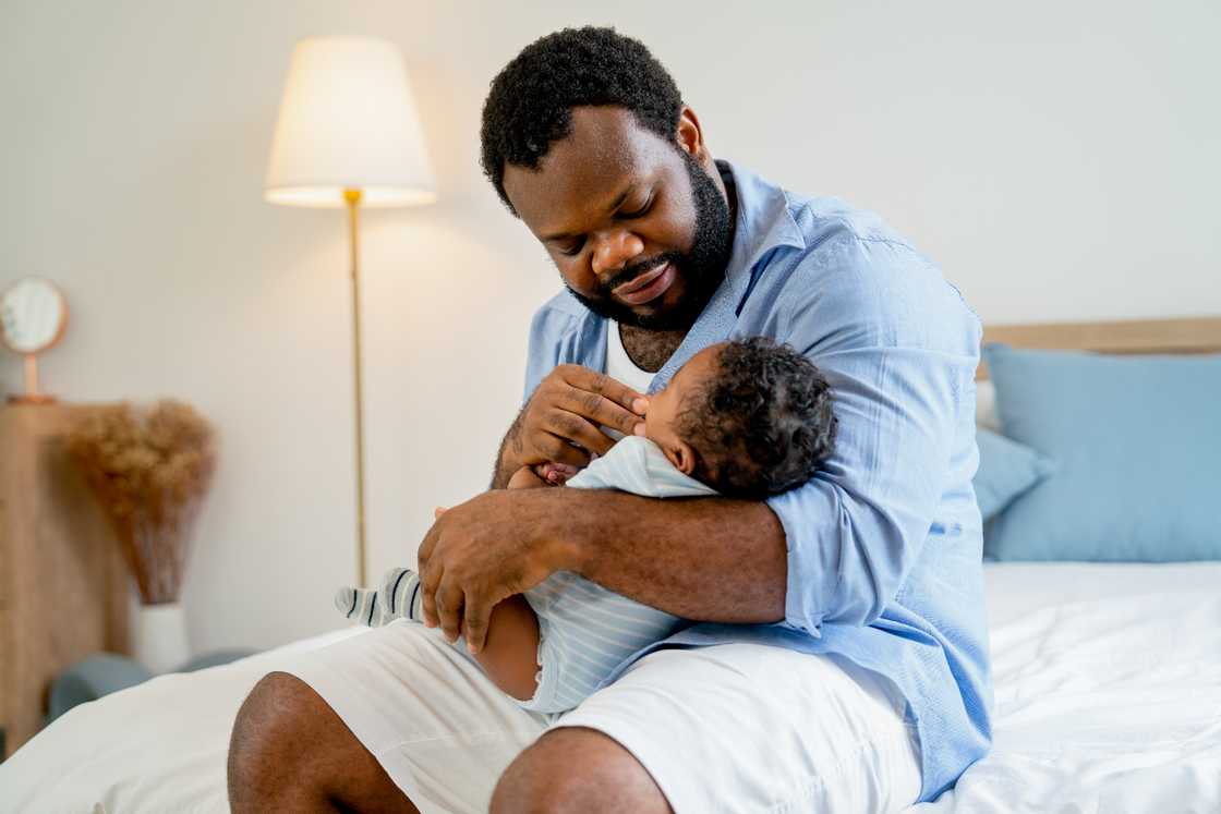 An African American father holds a newborn baby