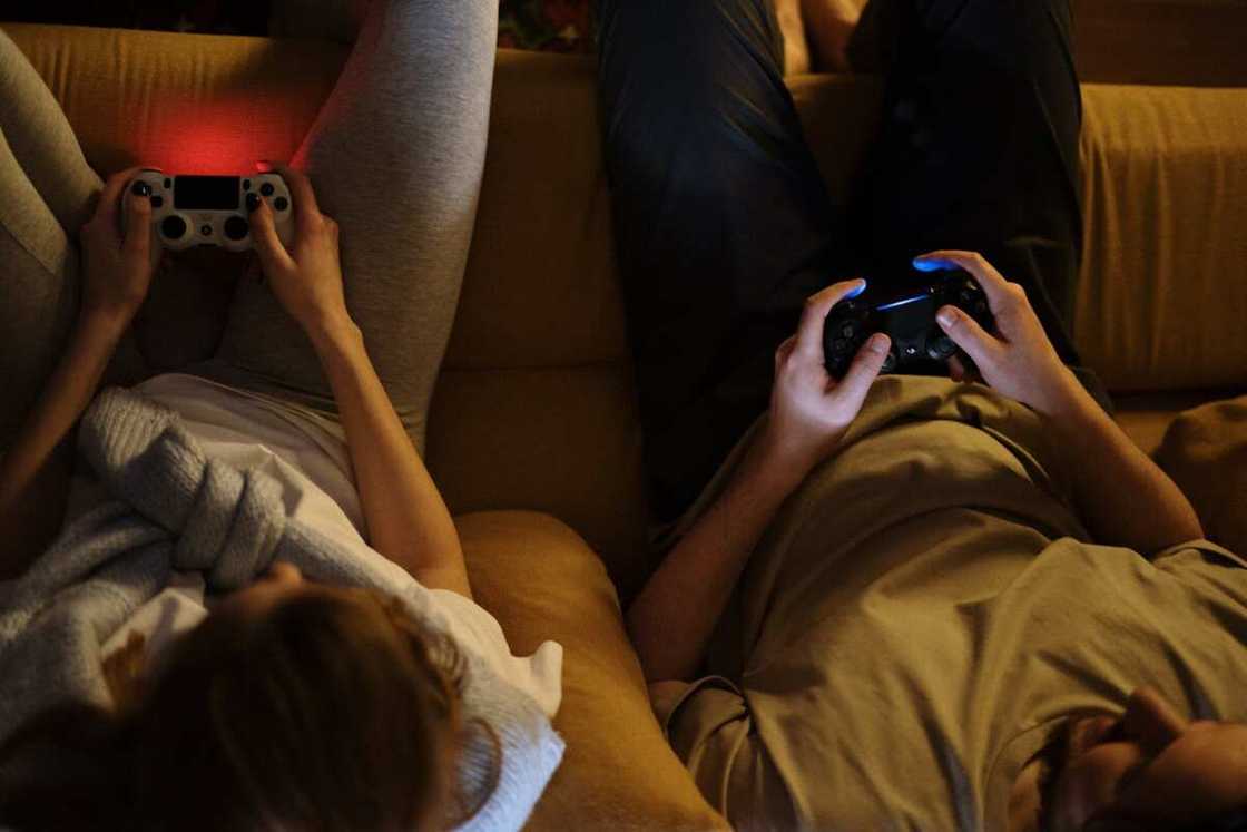 Two people gaming while holding gaming consoles in their hands