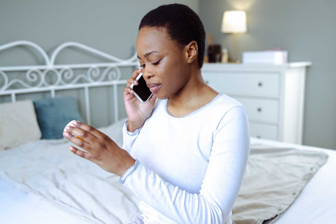 A young African American woman sits on the bed