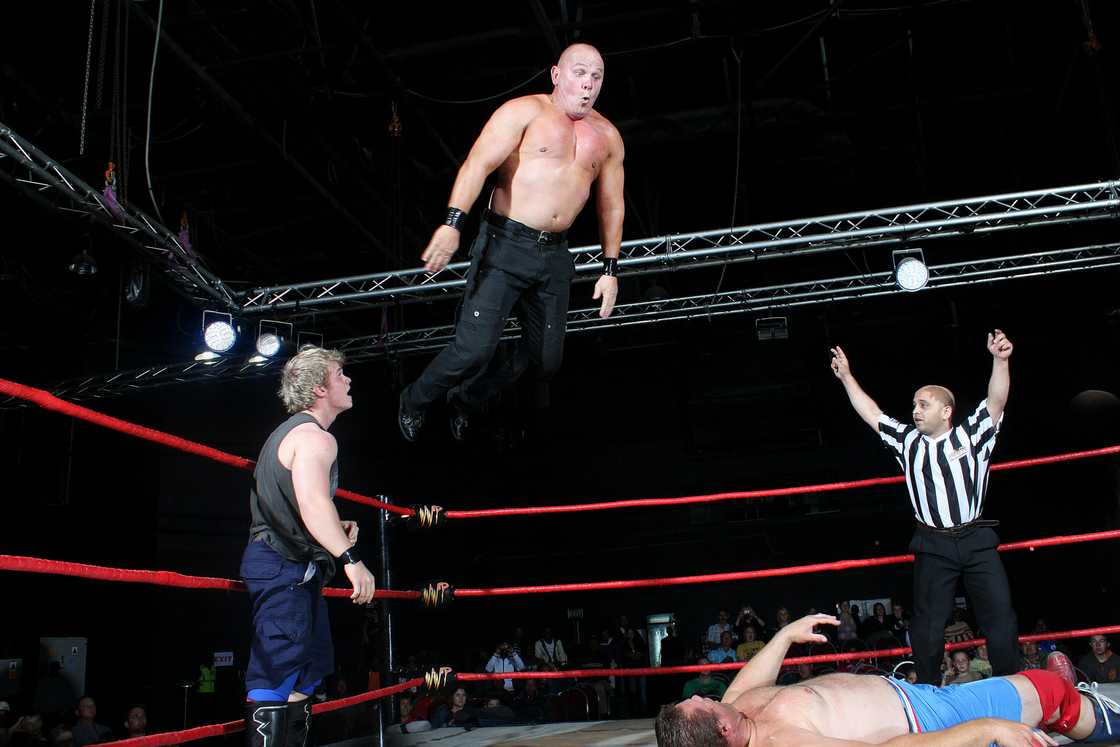 A wrestler jumping into a wrestling ring. A wrestler jumping into a wrestling ring.